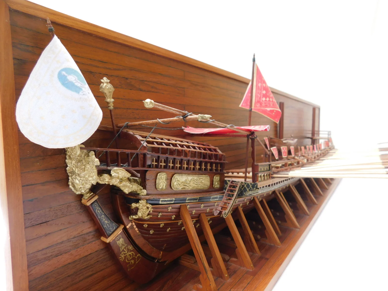 Handcrafted wooden half hull model ship of the 1694 French galley Real de France mounted on a luxury display board.