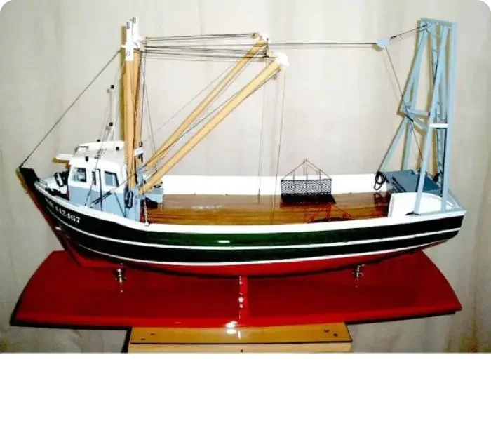 Artisan handcrafted wooden model boat of a classic traditional oyster dredger with fine deck details on a wooden base.