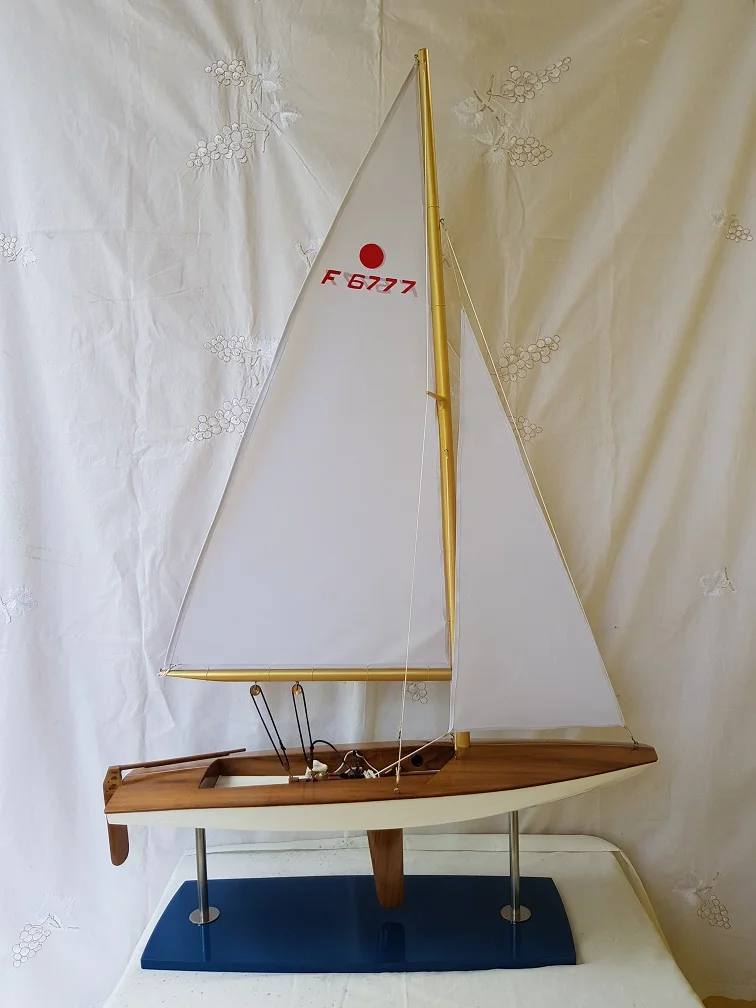 Wooden handcrafted scale model boat of the international Fireball class racing dinghy with open cockpit on display.